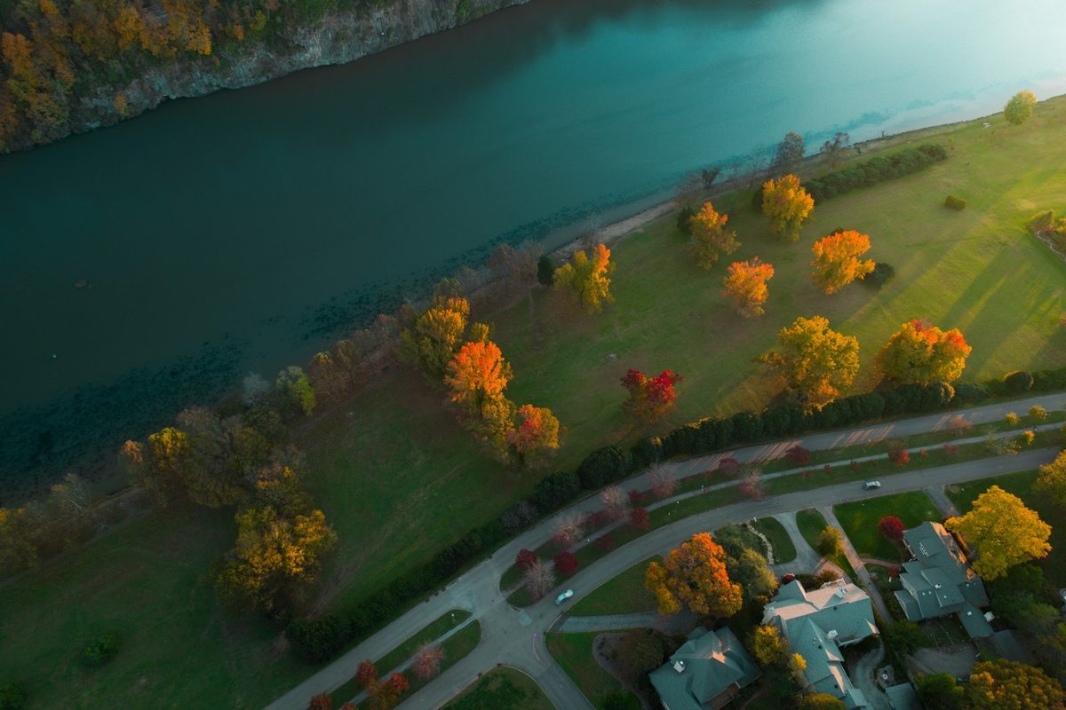 Aerial view of a riverside park and tree-lined boulevard on the Fort Loudoun stretch of the Tennessee River below Sequoyah Hills, with homes set well back from the teal water.