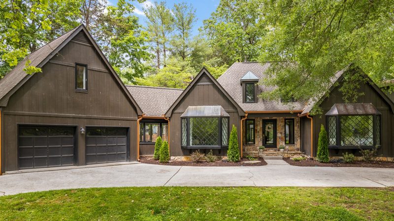 A dark-wood board-and-batten home from Farragut's early golf-course era, with diamond-pane bay windows and mature hardwoods shading the front lawn.