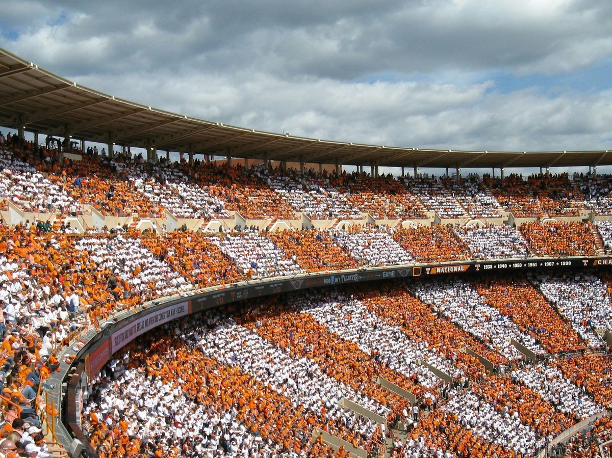 Neyland Stadium's stands checkered in alternating blocks of orange and white under a cloudy sky.