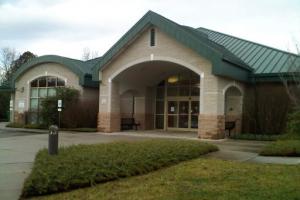 The Farragut Branch of the Knox County Public Library — a low single-story building with a green metal roof, stone-clad columns flanking a covered entrance, and a small bench out front.