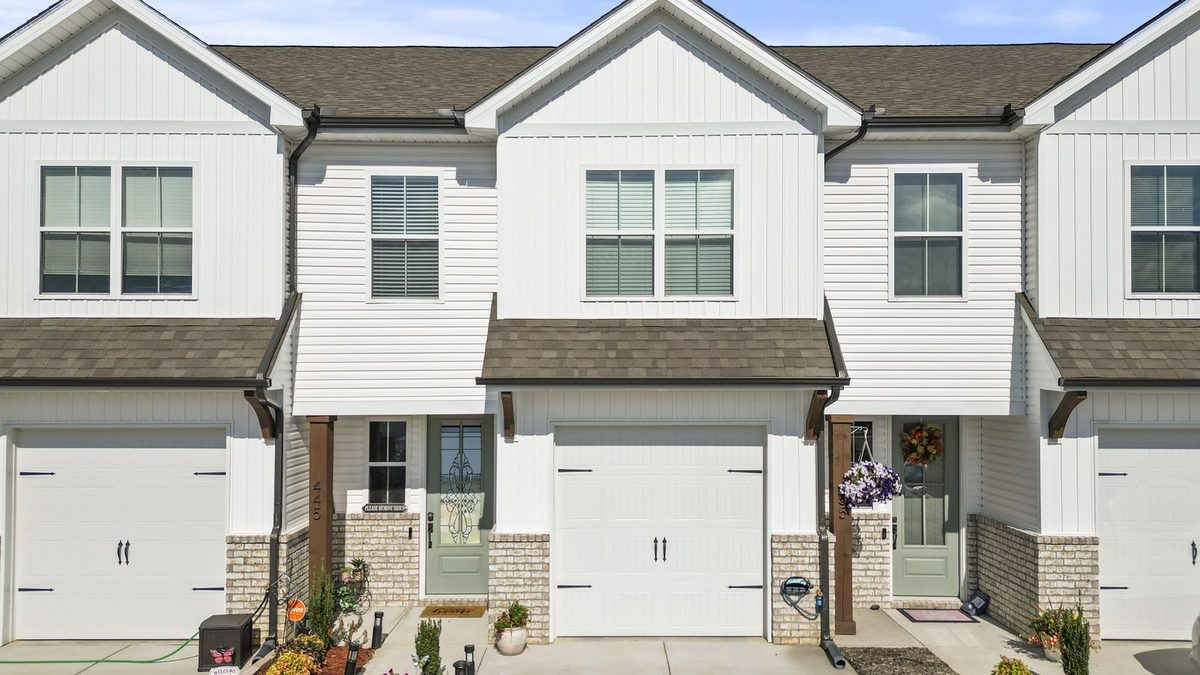 A row of white board-and-batten townhomes on a quiet West Knoxville street — the kind of low-maintenance home families buy to live close to Turkey Creek.