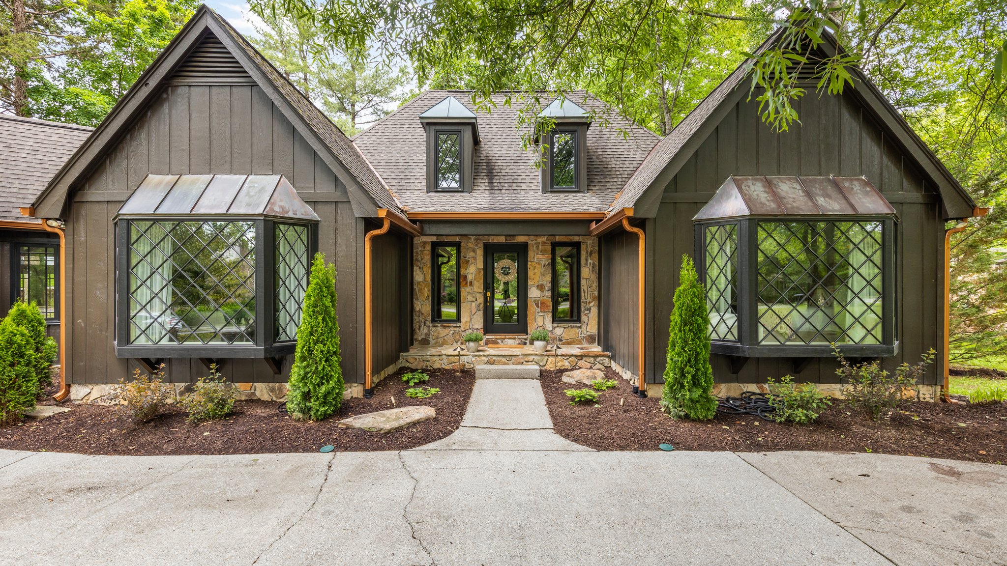 A spring-staged front entry of a red brick traditional West Knoxville home with a teal front door, a clay pot of mums, and dogwoods in early bloom — the first impression a buyer reads before they ever step inside.