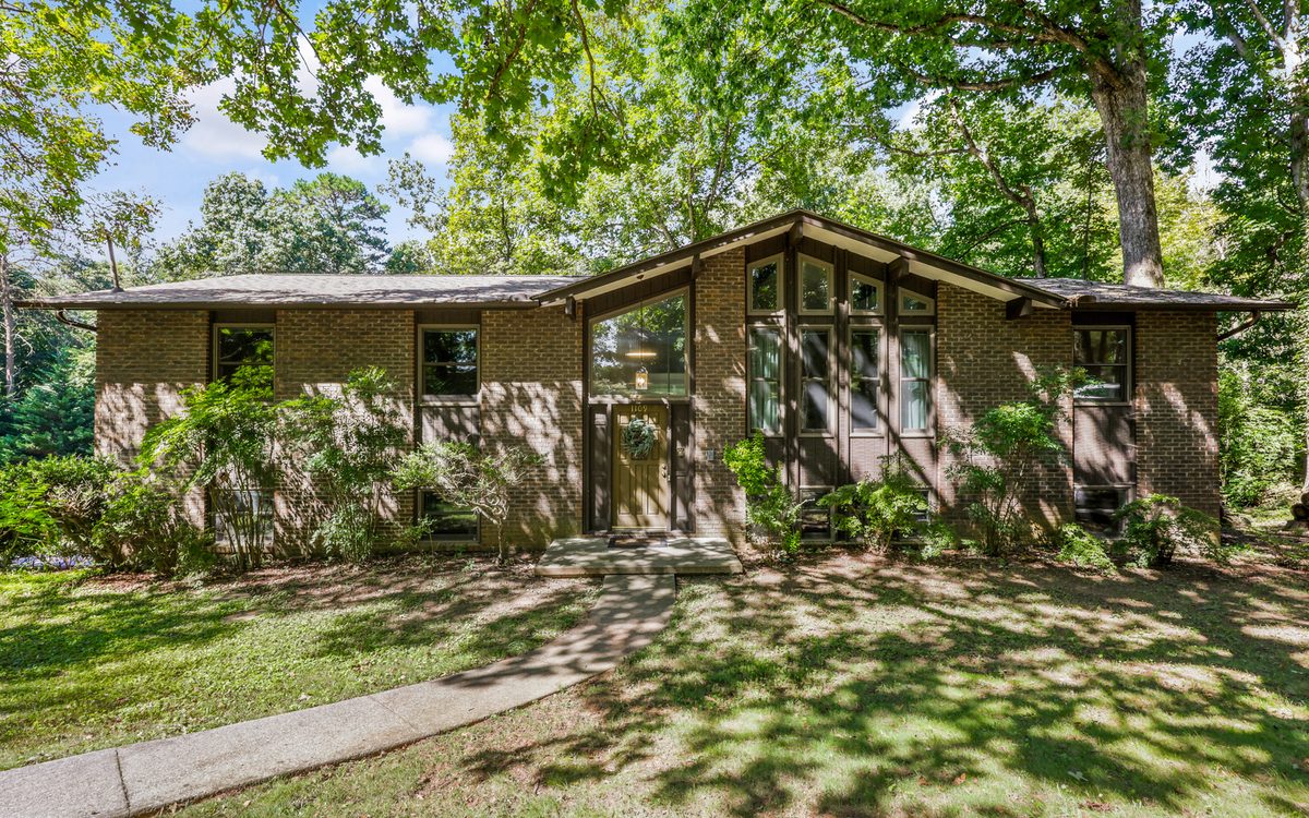 Front exterior of 1109 Venice Rd, a 1971 brick split-foyer with a two-story angled clerestory window wall, on a wooded lot in Gulf Park, West Knoxville