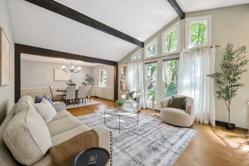 Living room with cathedral ceiling, exposed beams and the two-story angled window wall