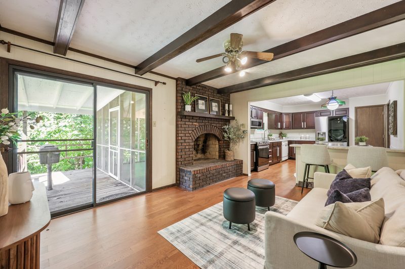 Beamed family room with brick fireplace, open to the kitchen and the screened-porch door
