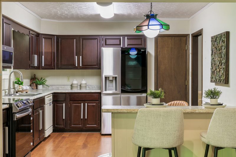 Eat-in kitchen with dark-wood cabinets, island seating and a stained-glass pendant