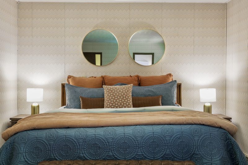 Bedroom with staged furnishings and a pair of round mirrors