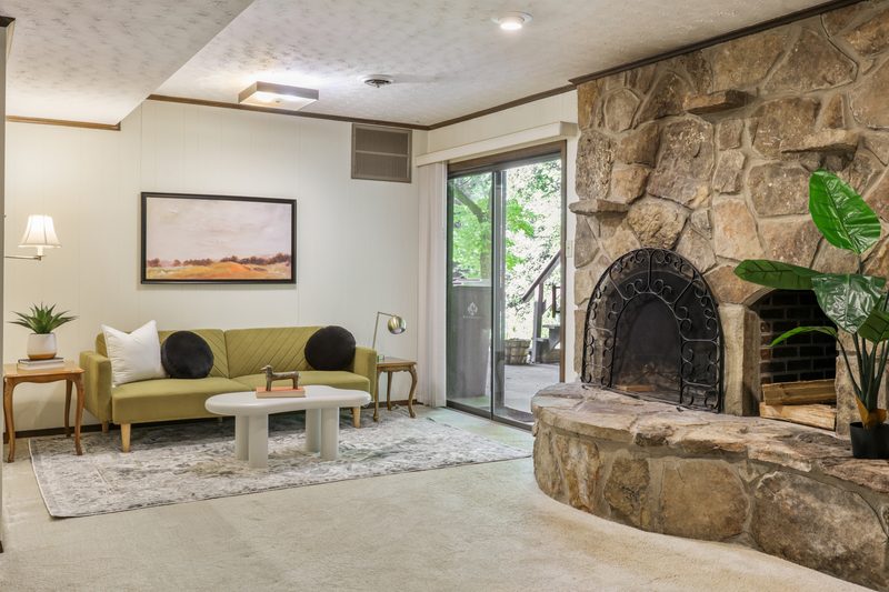 Lower-level rec room with floor-to-ceiling stone fireplace beside sliding doors to the patio